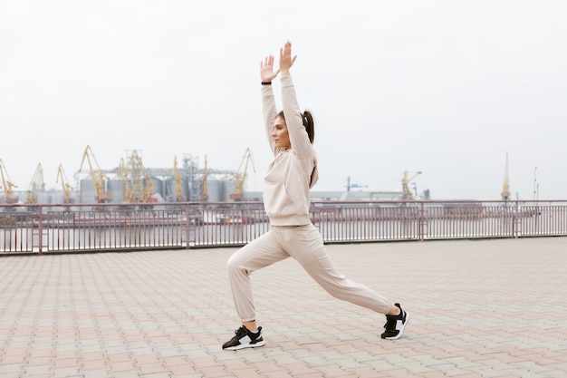 Femme en forme saine pratiquant des exercices de yoga asana sur le fond de la ville industrielle Warrior 1 pose