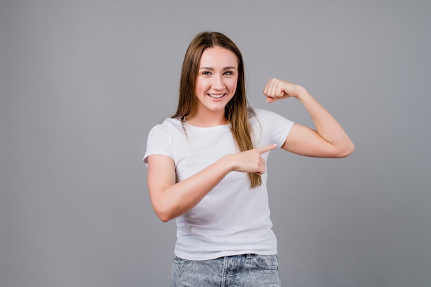 Femme forte montrant des biceps isolés sur gris