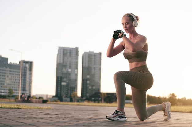 Femme forte de remise en forme fait de l'exercice et écoute de la musique dans des écouteurs dans la ville