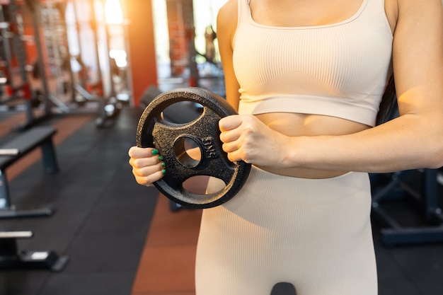 Une femme forte tient un disque pour une barre