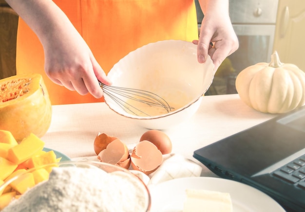 Une femme fouette des œufs et fait sa propre tarte à la citrouille en utilisant une recette trouvée sur Internet