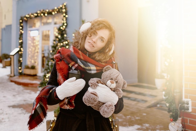 Femme en foulard et cache-oreilles en fourrure avec ours en peluche au marché de Noël