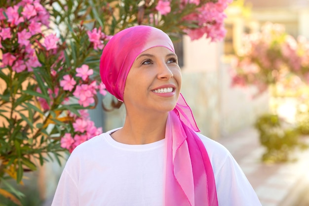 Femme avec foulard rose sur la tête. Sensibilisation au cancer