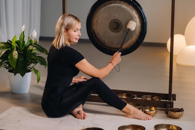 Une femme frappe un maillet avec un marteau sur un gong Un gong et un batteur à main pour le gong