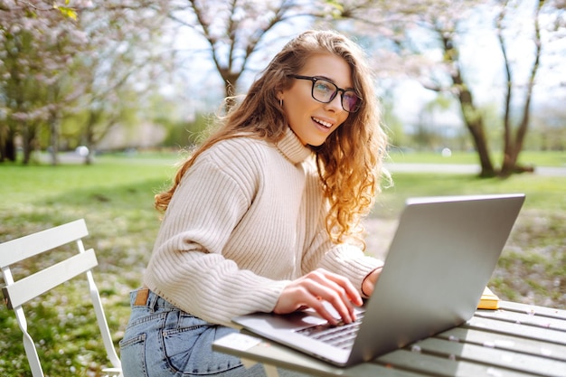 Une femme freelance heureuse assise au bureau avec un ordinateur portable Concept de nature et de style de vie urbain