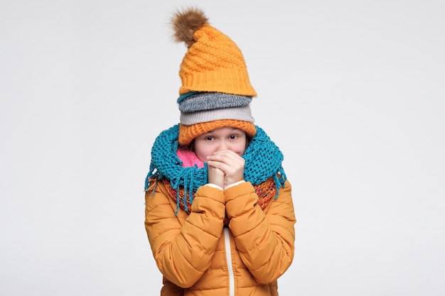 femme frissonnant de froid portant plusieurs chapeaux et écharpes d'hiver chauds