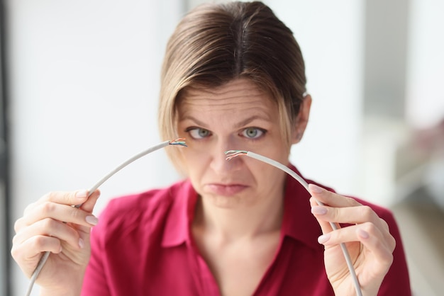 Une femme fronce les sourcils tenant un fil de réseau local cassé avec les mains une employée se sent contrariée par