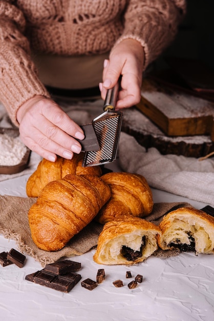 Une femme frotte du chocolat sur des croissants frais