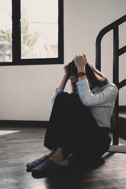 Femme frustrée assise seule à la maison souffrant de se sentir seule, bouleversée, triste, malheureuse et déprimée.