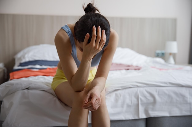 Une femme frustrée se couvre le visage de ses mains alors qu'elle est assise seule dans une pièce le concept de