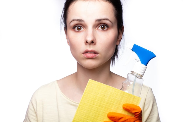 femme frustrée tenant des produits de nettoyage dans ses mains fond blanc