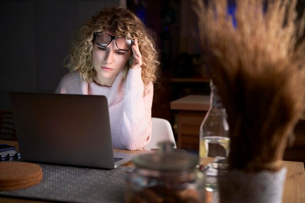 Femme frustrée travaillant sur un ordinateur portable jusque tard au travail