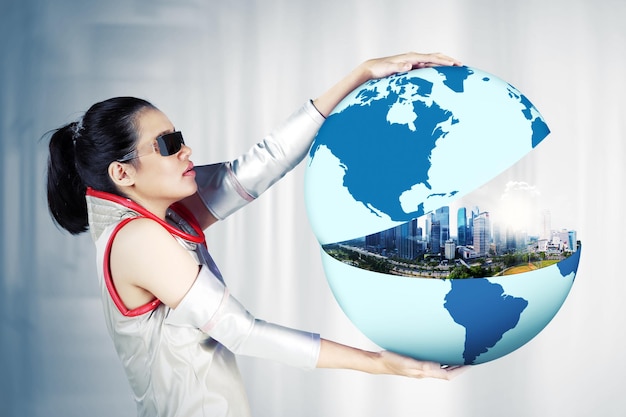 Photo femme futuriste montrant une ville moderne sur le globe