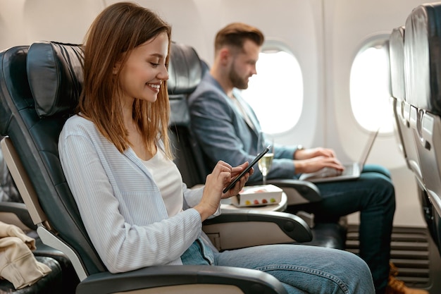 Photo femme gaie à l'aide du téléphone portable dans l'avion