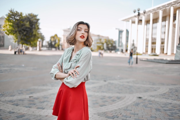 Femme gaie dans une jupe rouge sur la place dans la promenade de la ville