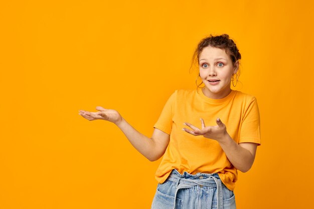 Femme gaie dans un t-shirt jaune posant des émotions fond jaune inchangé