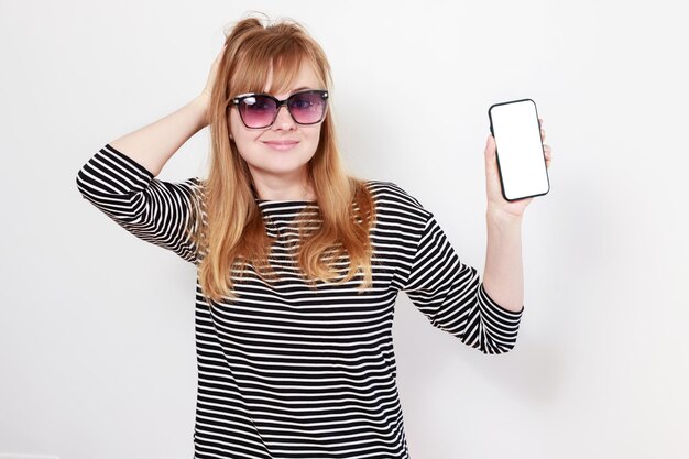 Femme gaie dans des verres avec une maquette de smartphone sur les vacances d'été de fond blanc