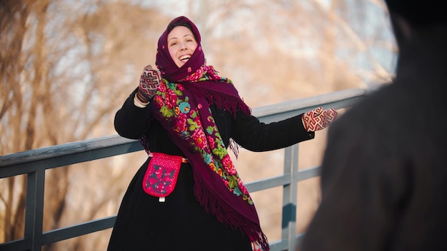 Une femme gaie du folklore russe dans une belle écharpe danse dans le parc