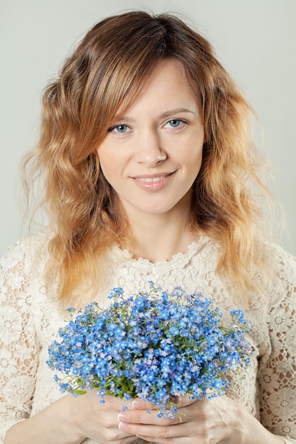 Femme gaie avec des fleurs bleues Peau de beauté naturelle sans retouche