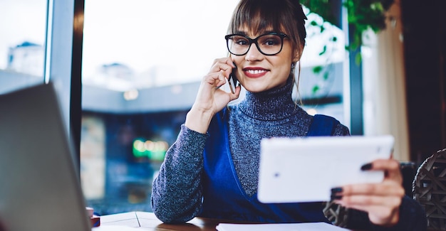 femme gaie positive du millénaire dans des lunettes optiques pour la correction de la vision en regardant la caméra