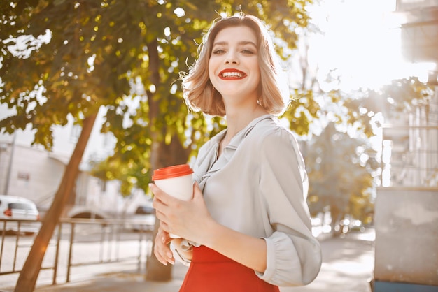 Femme gaie avec une tasse de café dehors pendant l'été