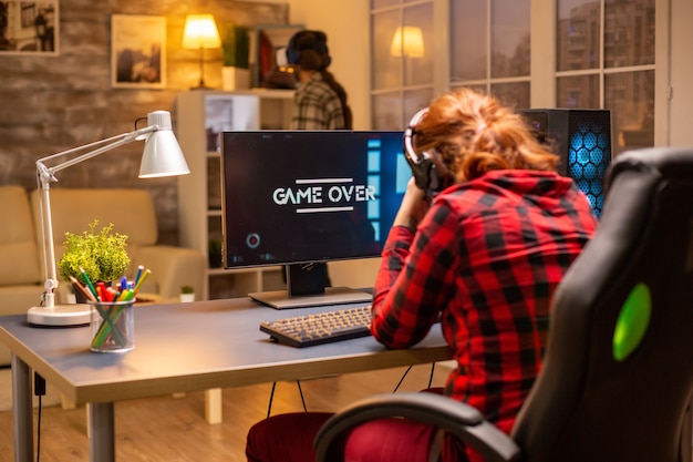 Femme gamer perdant à un jeu vidéo jouant tard dans la nuit dans le salon.