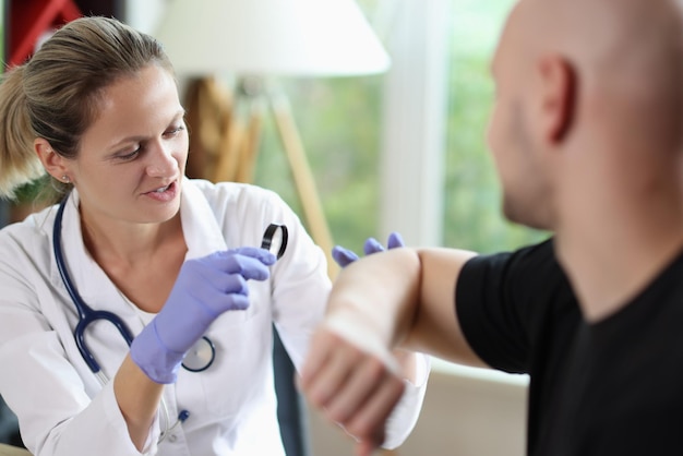 Femme gantée dermatologue examinant la peau d'un patient chauve avec une loupe