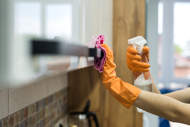 Femme en gants de caoutchouc et nettoyage du comptoir de cuisine avec une éponge. travaux ménagers