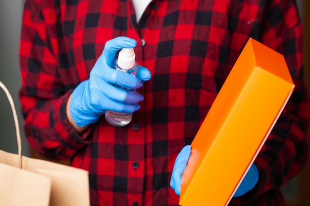 Photo femme en gants désinfecte l'emballage du produit à l'appartement