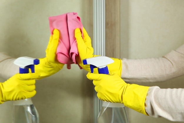 Photo une femme en gants essuie le miroir avec des détergents en gros plan