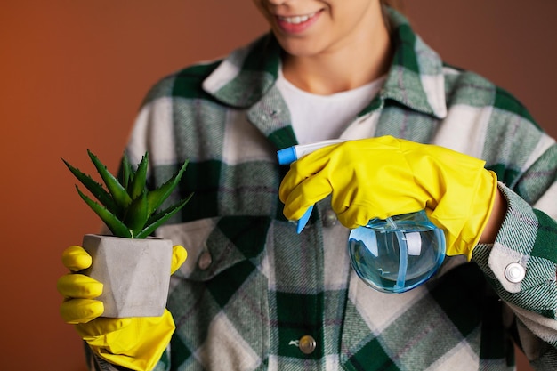 Femme en gants jaunes s'occupant des plantes d'intérieur à la maison