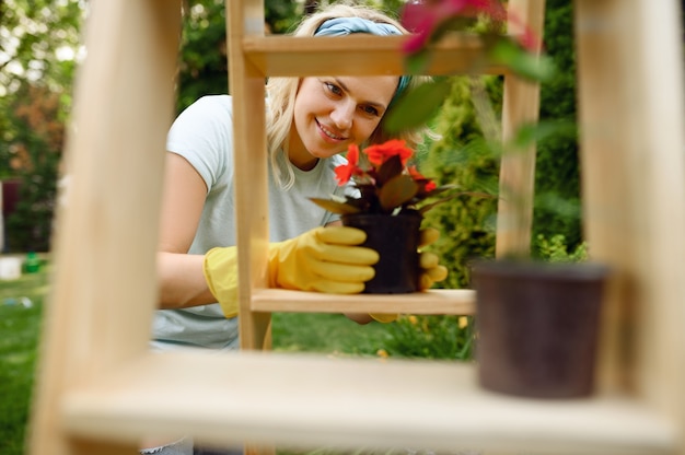 Femme en gants de plus en plus de fleurs dans des pots dans le jardin