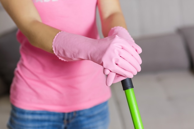 Femme avec des gants de protection à l'aide d'une vadrouille pour nettoyer le sol