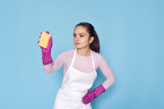 Femme en gants et tablier nettoyant nettoyant avec une éponge jaune