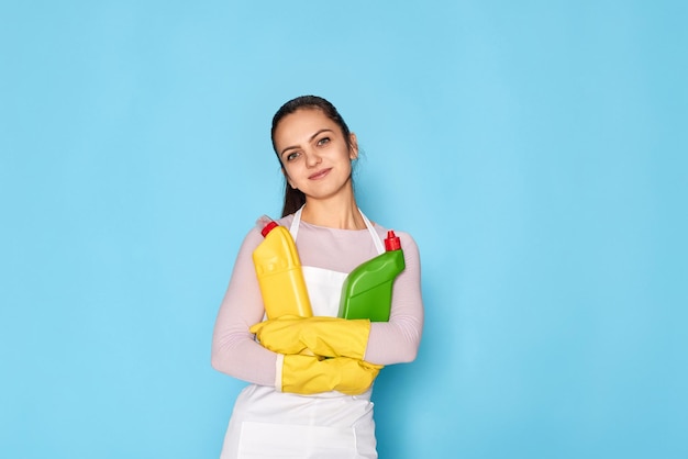 Femme en gants et tablier nettoyant tenant une bouteille de détergent