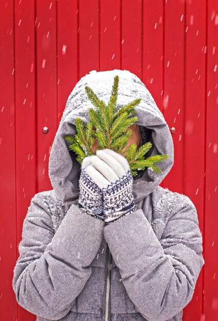 Photo femme en gants tricotés avec une branche de sapin