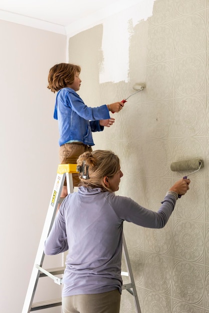 Une femme et un garçon de huit ans décorant une chambre en peignant des murs