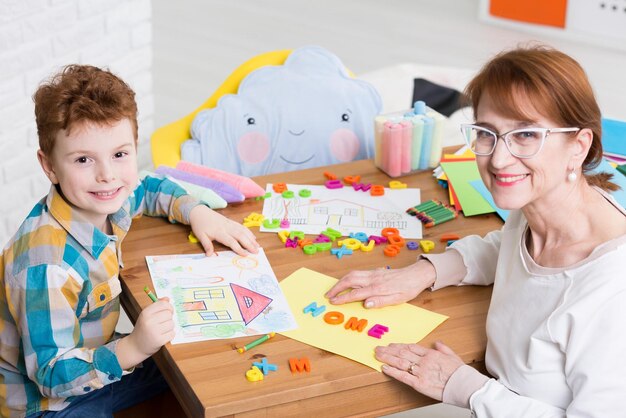 Une femme et un garçon sont assis à une table avec un papier qui dit maison.