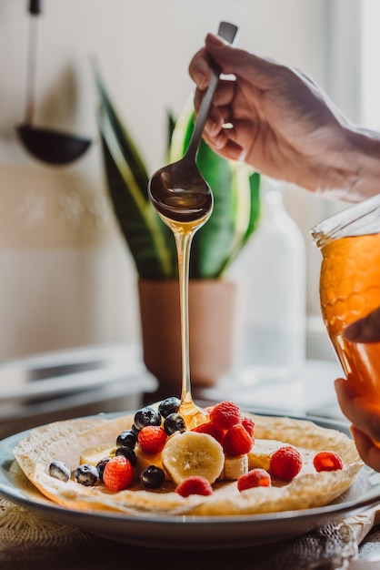 Femme garnissant de fines crêpes au miel