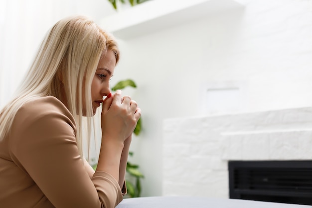 une femme à genoux prie à la maison