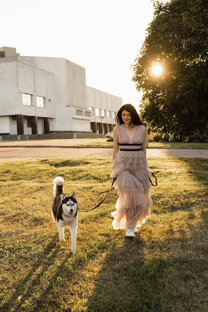 Femme géorgienne marchant avec un husky sibérien au coucher du soleil Jolie fille avec son adorable chien jouant dans la rue