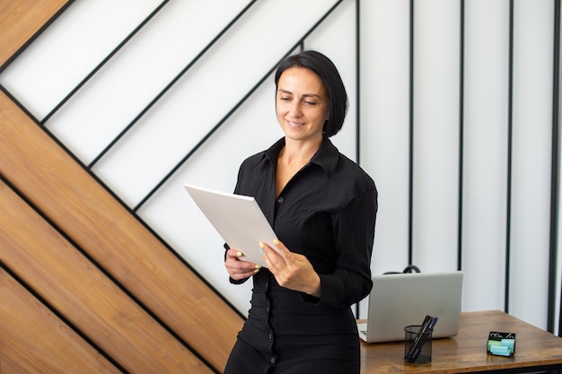 Une femme gestionnaire est assise sur un bureau au bureau