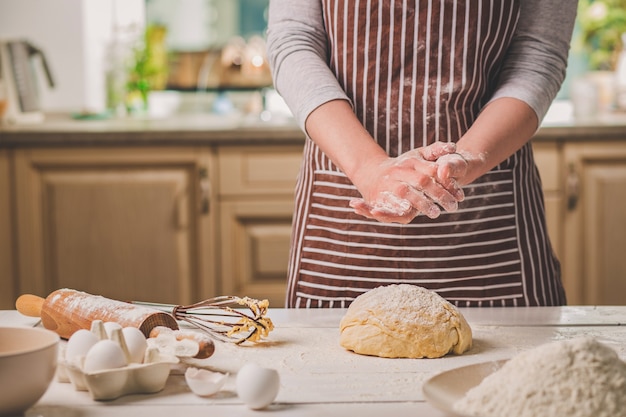 Femme gifler ses mains au-dessus de pâte agrandi. Baker termine sa boulangerie, secoue la farine de ses mains, libère de l'espace pour le texte. Boulangerie maison, concept de processus de cuisson