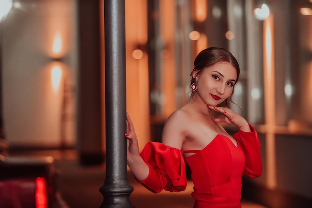 Une femme glamour en robe rouge posant dans la ville