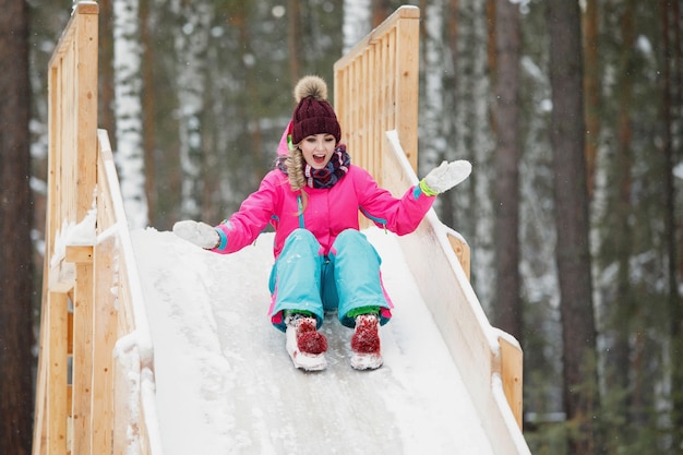 Photo femme glisser sur une colline en bois glacée un jour de neige.