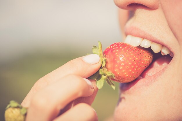 Photo la femme goûte une heure d'été de fraise organique mûre rouge