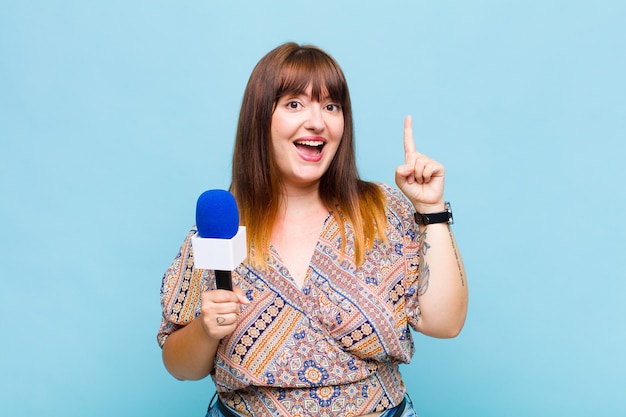 Femme grande taille se sentant comme un génie heureux et excité après avoir réalisé une idée, levant joyeusement le doigt, eureka!