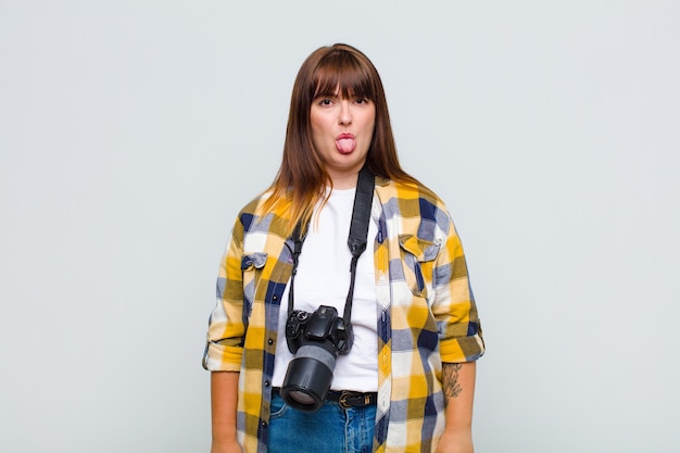 Femme grande taille se sentant dégoûtée et irritée, tirant la langue, n'aimant pas quelque chose de méchant et dégueulasse