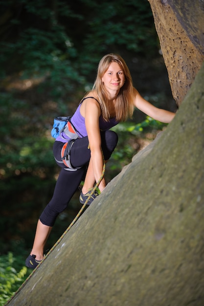 Femme grimpeur escalade avec une corde sur un mur rocheux