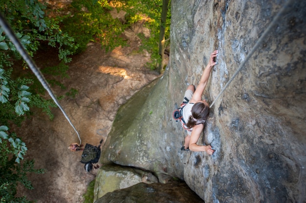 Femme grimpeur grimpe sur un mur rocheux